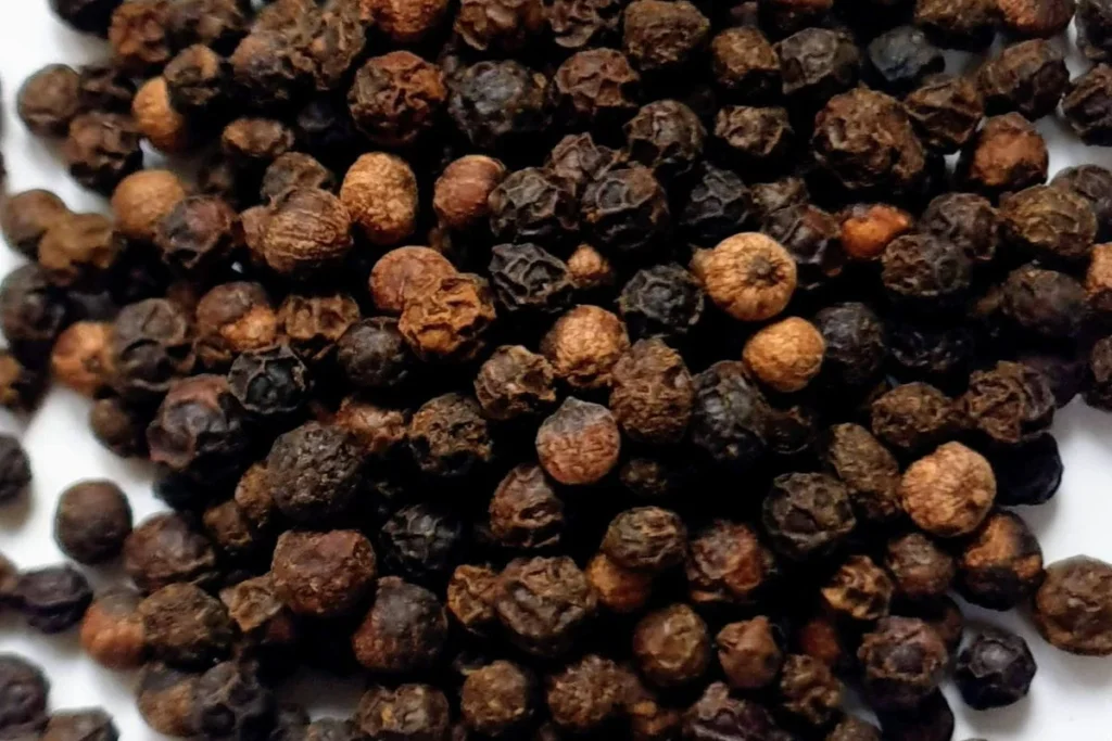 black pepper grinder beside Italian pantry staples on rustic wooden kitchen counter