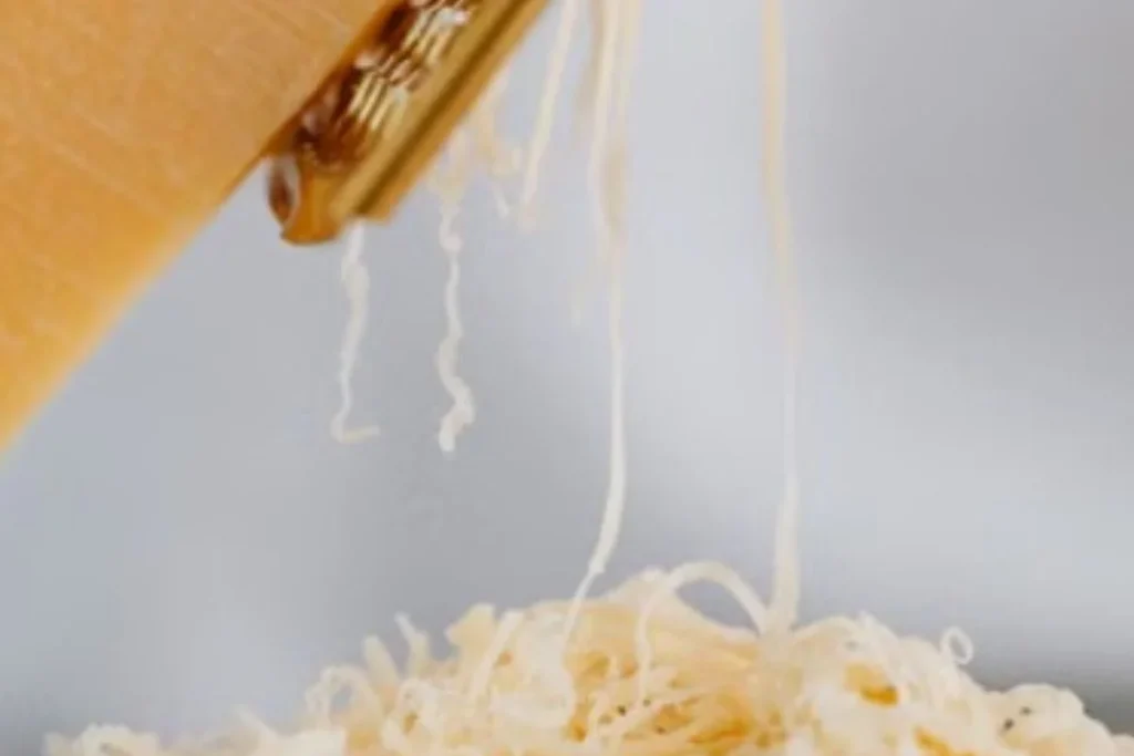 wedge of parmesan cheese with grater on rustic wooden cutting board